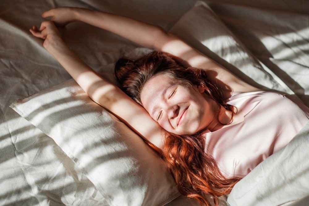 Mulher jovem acordando em uma cama. Suporte para texto sobre pesquisa de comportamento